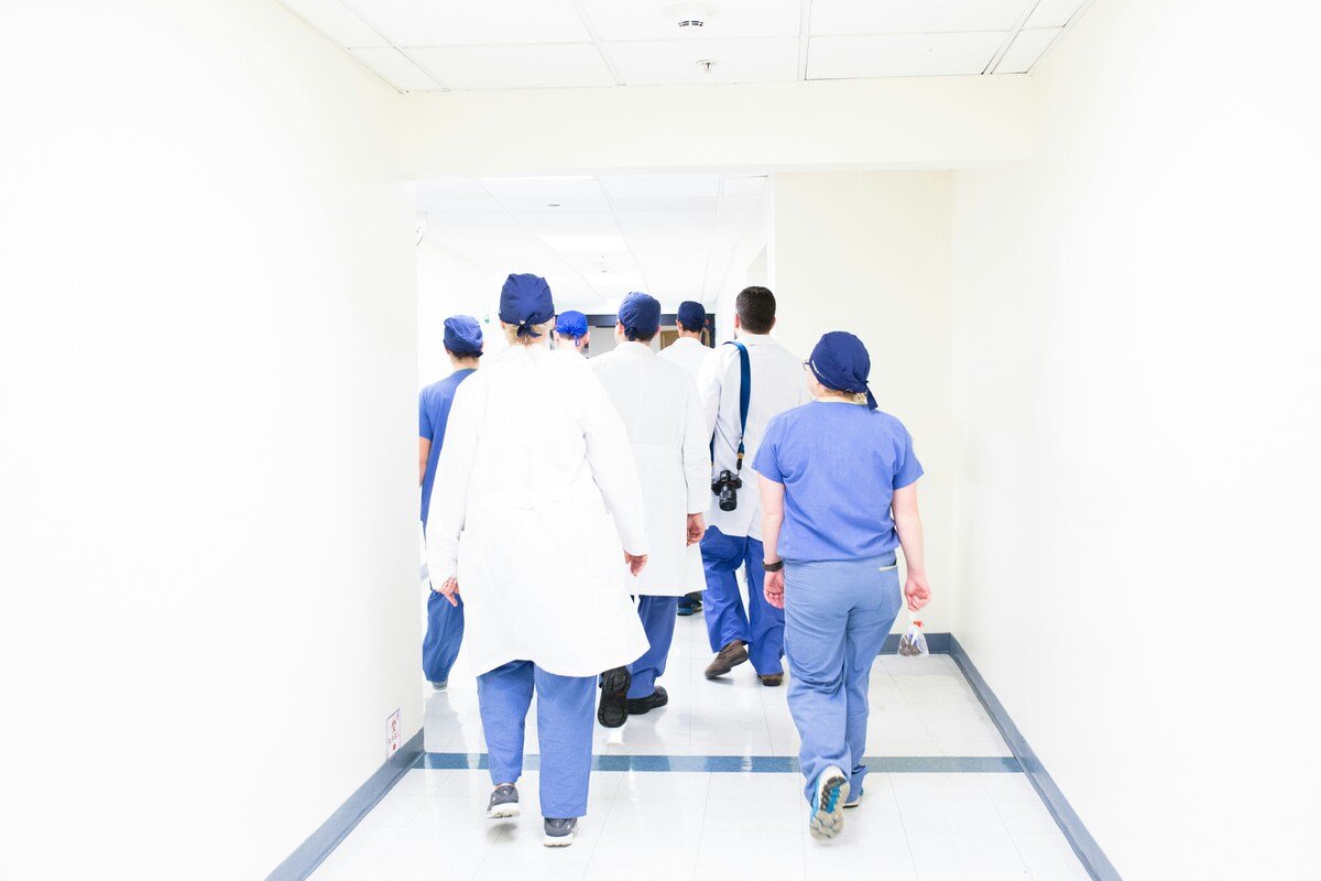Healthcare workers in scrubs and lab coats walking through hospital corridor, representing content written for healthcare workers