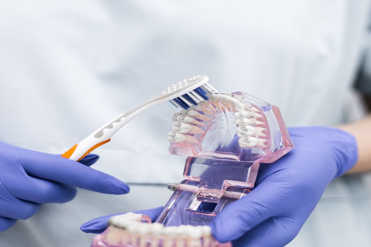 Oral health dentist demonstrating brushing technique on teeth model