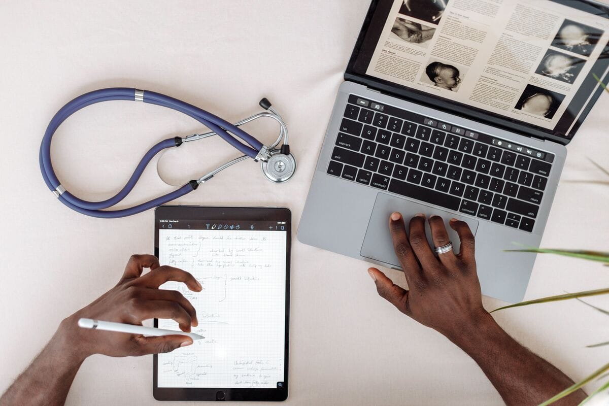 Doctor using laptop and tablet with stethoscope on desk, representing trusted health research